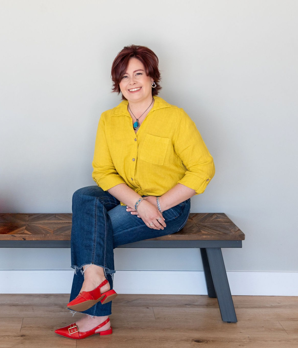 Melanie Rhora, keynote speaker, seated on a bench in a yellow blouse